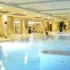 El Circuito Relax del Auditorio Beatriz Toledo cuenta con una tranquila piscina interior con tumbonas, una persona en bata y un nadador rodeados de una elegante iluminación y decoración. - ForTwo - Planes para parejas