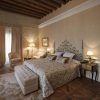 Descubra la elegancia de La suite perfecta de la mansión La Casa 1800 en Sevilla, con su cama decorativa, sus acogedores sillones y su suave iluminación. El techo con vigas de madera realza la majestuosidad de este elegante refugio. - ForTwo - Planes para parejas