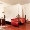 Un acogedor dormitorio con cama con dosel, manta colorida, muebles de madera y linterna decorativa sobre el suelo de baldosas rojas ofrece el ambiente perfecto para quienes buscan Suites románticas con jacuzzi en Alcoba del Rey de Sevilla (Sevilla). - ForTwo - Planes para parejas