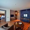 Experimente La suite presidencial del Hotel Barceló Sevilla Renacimiento en Sevilla: un refugio espacioso y moderno que cuenta con un dormitorio, sala de estar, elegantes pisos de madera y una llamativa pared de acento oscuro, que combina a la perfección comodidad y estilo. - ForTwo - Planes para parejas