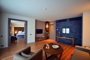 Experimente La suite presidencial del Hotel Barceló Sevilla Renacimiento en Sevilla: un refugio espacioso y moderno que cuenta con un dormitorio, sala de estar, elegantes pisos de madera y una llamativa pared de acento oscuro, que combina a la perfección comodidad y estilo. - ForTwo - Planes para parejas