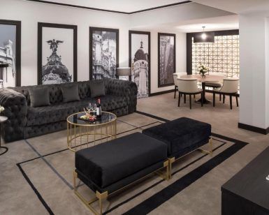 Descubra la elegancia de la Suite presidencial en el hotel Meliá Castilla (Madrid), que cuenta con una refinada sala de estar con un sofá negro, una mesa redonda y llamativas fotografías de la ciudad en blanco y negro que complementan a la perfección el elegante comedor. - ForTwo - Planes para parejas