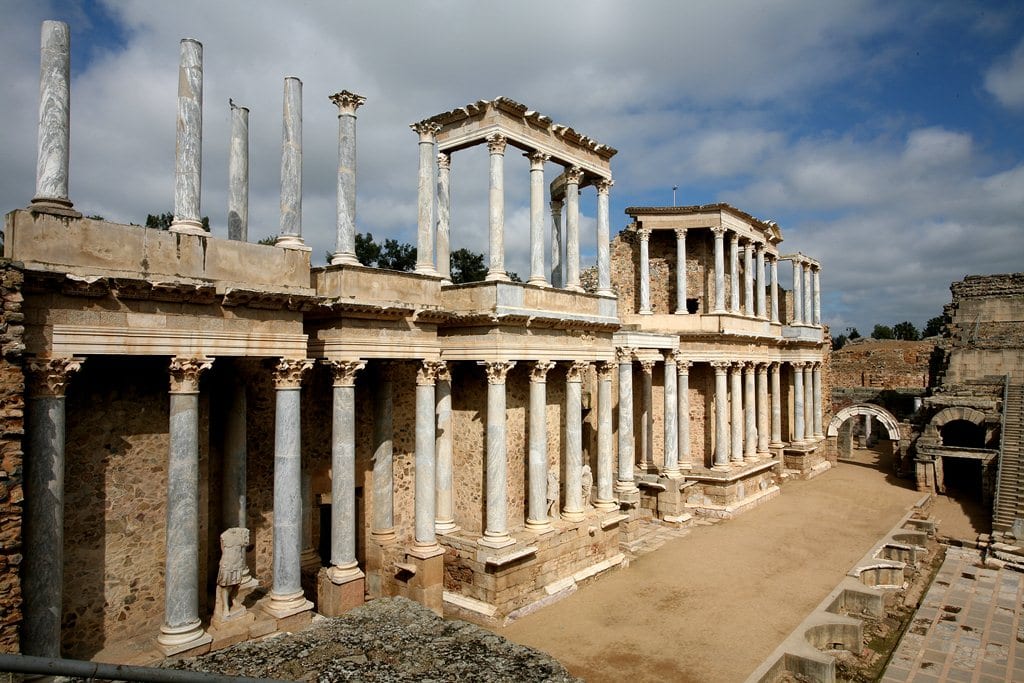 El Restaurante Abades en Ronda ofrece una experiencia de menú romántico con elegantes interiores que presentan mesas redondas con manteles blancos, equipadas con cristalería y platos, complementados con arte en las paredes. - ForTwo - Planes para parejas