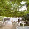 Junto a una exuberante vegetación, esta lujosa cafetería al aire libre en el Hotel Palacio de los Patos ofrece serenas vistas a la fuente y un sofisticado bar, que encarna el tranquilo ambiente de spa de la "Escapada de lujo en el hotel Palacio de los Patos con spa incluido (Granada). - ForTwo - Planes para parejas