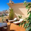 La Suite con terraza y Spa del Hotel Boutique Hurso (Madrid) cuenta con dos tumbonas, una mesa de mimbre y exuberantes plantas bajo un cielo azul despejado. Disfrute hoy de su oasis de serenidad. - ForTwo - Planes para parejas
