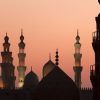 Las siluetas de las cúpulas y los minaretes de una mezquita contra una puesta de sol de color rosa anaranjado evocan el encanto encantador del "Viaje a Egipto y el templo de Abu Simbel en 8 días". - ForTwo - Planes para parejas