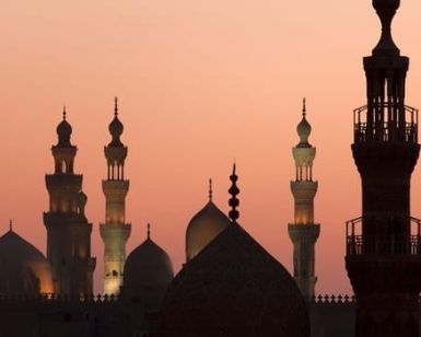 Las siluetas de las cúpulas y los minaretes de una mezquita contra una puesta de sol de color rosa anaranjado evocan el encanto encantador del "Viaje a Egipto y el templo de Abu Simbel en 8 días". - ForTwo - Planes para parejas