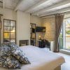 Disfrute de una acogedora habitación en el Hotel Torre del Canónigo (Ibiza), decorada con detalles en blanco, almohadas estampadas, televisor y acceso al balcón. Disfrute del encanto de las vigas de madera rústicas y los detalles de piedra en las paredes, creando un ambiente acogedor. - ForTwo - Planes para parejas