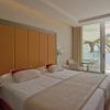 Disfrute de una habitación contemporánea en el Hotel Torre del Mar en Ibiza, equipada con dos camas individuales, un cabecero naranja y un balcón que ofrece impresionantes vistas al mar y palmeras ondulantes. - ForTwo - Planes para parejas