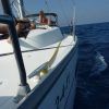 Relajándose en un velero en el océano bajo un cielo azul claro, una persona disfruta de una Salida en barco compartido en Barcelona cerca de la vibrante ciudad. - ForTwo - Planes para parejas