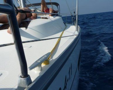 Relajándose en un velero en el océano bajo un cielo azul claro, una persona disfruta de una Salida en barco compartido en Barcelona cerca de la vibrante ciudad. - ForTwo - Planes para parejas