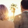 Una pareja, de espaldas, disfruta de un atardecer alicantino enmarcado por palmeras. La mujer de pelo rosa y el hombre con chaqueta a cuadros crean un momento perfecto en su "Sesión de fotos en pareja con Melina Bolopá (Alicante)". - ForTwo - Planes para parejas