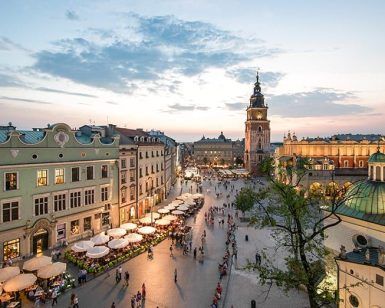 Vista aérea de una bulliciosa plaza europea al atardecer en Cracovia, que muestra edificios históricos, una torre y vibrantes cafés al aire libre: un entorno ideal para comenzar su Tour gratuito por la ciudad de Cracovia. - ForTwo - Planes para parejas