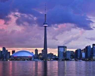 El "Tour por el este de Canadá" presenta el horizonte de Toronto al atardecer, donde la Torre CN y las nubes de colores se reflejan de forma impresionante en las tranquilas aguas. - ForTwo - Planes para parejas