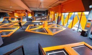En Urban Planet Jump Las Rejas, Madrid, los visitantes saltan enérgicamente en coloridos trampolines naranjas y negros en el bullicioso parque interior. - ForTwo - Planes para parejas