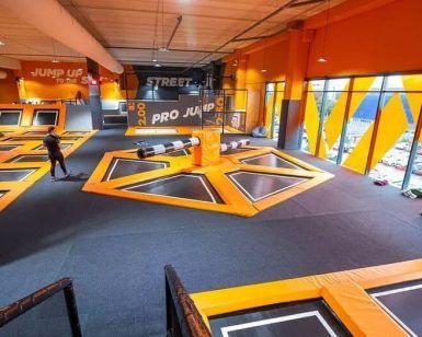 En Urban Planet Jump Las Rejas, Madrid, los visitantes saltan enérgicamente en coloridos trampolines naranjas y negros en el bullicioso parque interior. - ForTwo - Planes para parejas