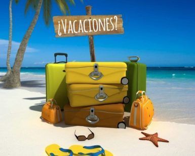 Maletas coloridas en una playa soleada con un cartel de "¿Vacaciones?" junto a palmeras, chanclas y una estrella de mar te invitan a cambiar tus planes de escape room en Madrid por relajación. Producto: "¿Vacaciones?" - Un escape room de Dale al coco (Madrid). - ForTwo - Planes para parejas
