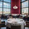 Restaurante Vertical en Valencia ofrece una elegante experiencia gastronómica con mesas redondas vestidas con manteles blancos, grandes ventanales que ofrecen vistas panorámicas de la ciudad y una decoración moderna que añade sofisticación. - ForTwo - Planes para parejas