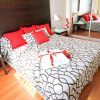 Cree un retiro inspirado en Sevilla con elementos modernos y elegantes, como una colcha estampada, almohadas rojas y puertas de armario con espejos, ideal después de disfrutar de "Escapada con desayuno, bañera de hidromasaje y entradas al Gran Casino Aljarafe (Sevilla). - ForTwo - Planes para parejas