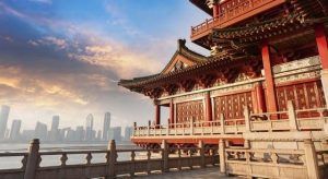 La escena presenta un edificio tradicional chino de "Viaje a China: de Pekín a Shanghai", con vistas al vibrante horizonte de Shanghai al atardecer, con detalles ornamentados bajo un cielo nublado. - ForTwo - Planes para parejas