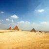 Embárcate en el "Viaje a Egipto de 8 días" de 8 días a través del desierto, donde se alzan las majestuosas Pirámides de Giza bajo un cielo azul con nubes dispersas. - ForTwo - Planes para parejas