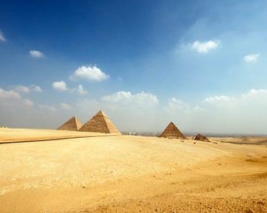 Embárcate en el "Viaje a Egipto de 8 días" de 8 días a través del desierto, donde se alzan las majestuosas Pirámides de Giza bajo un cielo azul con nubes dispersas. - ForTwo - Planes para parejas