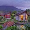 Cabañas ubicadas en una exuberante vegetación contra un fondo montañoso con cielos nublados, crean el escenario perfecto para el Viaje a Costa Rica de 8 días para explorar los encantadores paisajes de Costa Rica. - ForTwo - Planes para parejas