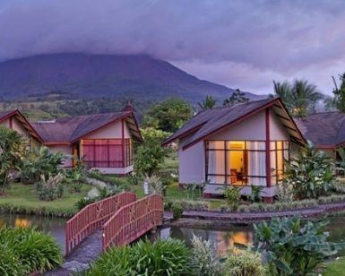 Cabañas ubicadas en una exuberante vegetación contra un fondo montañoso con cielos nublados, crean el escenario perfecto para el Viaje a Costa Rica de 8 días para explorar los encantadores paisajes de Costa Rica. - ForTwo - Planes para parejas