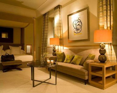 Escápese al elegante Hotel Villa Oniria—Granada, que ofrece una lujosa cama doble, un cómodo sofá, una mesa de centro de cristal con velas y paredes decoradas con obras de arte. Perfecto para el romance o la serenidad en su exquisito spa con nuestra "Escapada romántica con spa en el hotel Villa Oniria 4 estrellas". - ForTwo - Planes para parejas