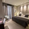 Alójese en una habitación contemporánea en el Hotel Vincci Mercat de Valencia, con cama doble, dos lámparas de noche, escritorio con silla, elegantes obras de arte en la pared y un amplio ventanal con cortinas. Disfrute de una experiencia excepcional llena de sofisticación. - ForTwo - Planes para parejas