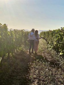 En medio de exuberantes vides verdes, una pareja disfruta de un "Día romántico de vino y gastronomía entre viñedos" en Barcelona, saboreando la promesa del viñedo iluminado por el sol de buen vino y ricos manjares. - ForTwo - Planes para parejas