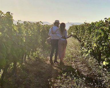 En medio de exuberantes vides verdes, una pareja disfruta de un "Día romántico de vino y gastronomía entre viñedos" en Barcelona, saboreando la promesa del viñedo iluminado por el sol de buen vino y ricos manjares. - ForTwo - Planes para parejas