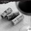Tres corchos de vino descansan delicadamente sobre un paño blanco cerca de una elegante copa, capturando la esencia de "Cata de vino bajo las estrellas en Las Moradas de San Martín (Madrid)", un tesoro madrileño. - ForTwo - Planes para parejas