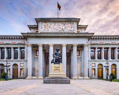 Vista frontal del Museo del Prado en Madrid, con una estatua de Velázquez al atardecer. Complemente su visita con una "Visita guiada por el Museo del Prado". - ForTwo - Planes para parejas