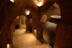 Revisite la antigua bodega de piedra, poco iluminada, de la Bodega Muñoz Martín en Madrid, con sus pasadizos abovedados y una urna de barro. Una joya infravalorada entre los viñedos, captura el encanto atemporal de la herencia vinícola española. Incluye cata opcional. - ForTwo - Planes para parejas