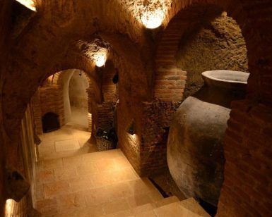 Revisite la antigua bodega de piedra, poco iluminada, de la Bodega Muñoz Martín en Madrid, con sus pasadizos abovedados y una urna de barro. Una joya infravalorada entre los viñedos, captura el encanto atemporal de la herencia vinícola española. Incluye cata opcional. - ForTwo - Planes para parejas