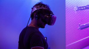 Un usuario se pone los auriculares Realidad Virtual en Pareja en Oasis VR Experience en San Sebastián de los Reyes, Madrid, y entra en un vibrante mundo virtual inundado de tonos morados y azules. - ForTwo - Planes para parejas