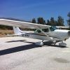 Un Vuelo en avioneta en pareja (Málaga), protagonizado por un pequeño avión blanco, está estacionado en una pista soleada con árboles y el vibrante cielo azul de Málaga de fondo. - ForTwo - Planes para parejas
