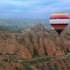 La experiencia Volar en Globo en Guadix (Granada) ofrece un colorido paseo en globo aerostático, flotando elegantemente sobre paisajes rocosos y exuberantes campos verdes bajo un cielo nublado, creando recuerdos inolvidables. - ForTwo - Planes para parejas