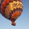 Un romántico vuelo en globo con Green Aerostacion (Sevilla) comienza contra el cielo azul claro, mostrando un colorido globo aerostático con pasajeros en la canasta. - ForTwo - Planes para parejas