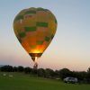 Un Vuelo en globo tradicional en Barcelona con Globus con los colores del arco iris está atado en un campo de hierba al atardecer cerca de Barcelona, con un vehículo cerca. - ForTwo - Planes para parejas