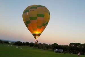 Un Vuelo en globo tradicional en Barcelona con Globus con los colores del arco iris está atado en un campo de hierba al atardecer cerca de Barcelona, con un vehículo cerca. - ForTwo - Planes para parejas