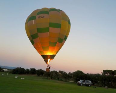 Un Vuelo en globo tradicional en Barcelona con Globus con los colores del arco iris está atado en un campo de hierba al atardecer cerca de Barcelona, con un vehículo cerca. - ForTwo - Planes para parejas