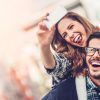 Una mujer sonriente lleva a cuestas a su pareja, ambos haciendo signos de paz para una selfie durante su Viaje sorpresa en pareja por Europa con Waynabox. - ForTwo - Planes para parejas