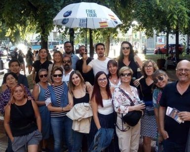 Un grupo alegre se encuentra bajo los árboles y los coches aparcados, sosteniendo con orgullo su paraguas del Free Tour. ¡Es un día perfecto para Freetour en Budapest con White Umbrella Tours en la hermosa Budapest!. - ForTwo - Planes para parejas