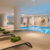 Relájese en tumbonas con toallas verdes en la piscina cubierta del Meliá Madrid Princesa, rodeado de máquinas de gimnasio. Disfrute de la rejuvenecedora Hidroterapia en el Spa Yhi Wellness del hotel Meliá Madrid Princesa 5 estrellas para una experiencia revitalizante. - ForTwo - Planes para parejas