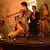En un espacio oscuro de El Templo del Flamenco, una bailarina con traje actúa mientras dos mujeres sentadas aplauden, creando una experiencia inolvidable de Espectáculo + Menú tapeo. - ForTwo - Planes para parejas