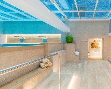 Disfrute de la lujosa piscina cubierta del Sallés Hotel Pere IV, con suelos de madera, un impresionante techo de cristal y toallas. Disfrute del Circuito de Spa + Menú Saludable en el Sallés Hotel Pere IV (Barcelona) mientras admira la exquisita decoración de la pared. - ForTwo - Planes para parejas