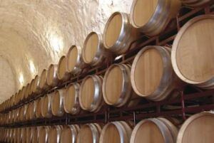 En la bodega de paredes de piedra de Bodegas Muñana, filas de barricas de madera se apilan meticulosamente, creando el entorno perfecto para una experiencia Cata de Vinos en Bodegas Muñana para Dos. - ForTwo - Planes para parejas