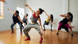 Cinco mujeres bailando flamenco con pasión en un estudio, encarnando el espíritu vibrante de Sevilla. Vívelo con "Clases de Baile en Sevilla: Flamenco, Ballet, Sevillanas, Bailes latinos y de salón. - ForTwo - Planes para parejas